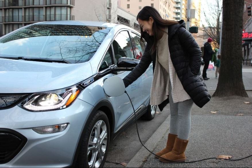 A women charges an electric sedan.