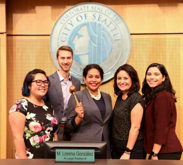 Brianna Thomas holds the gavel and poses next to Councilmember Gonzalez and her fellow staff members in Council Chambers.