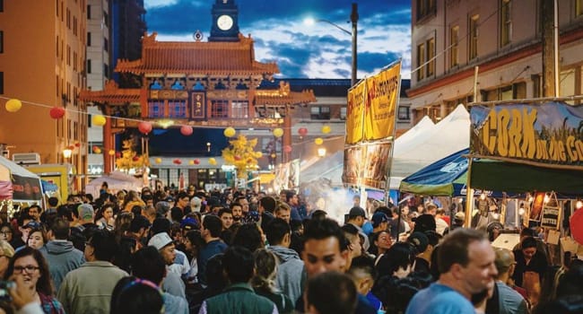 A crowded Chinatown-International District Night Market with a view of the Chinatown gate near the King Street station.