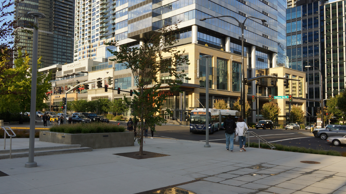 A photo of a small pedestrian plaza near an intersection.