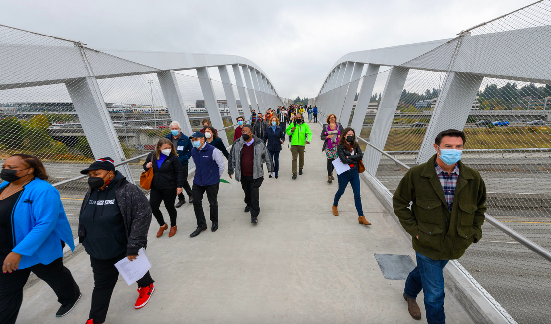 A photo of people walking on a pedestrian bridge over Interstate 5.