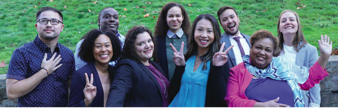 A photo of a racially diverse group of adults in professional attire waving and smiling.