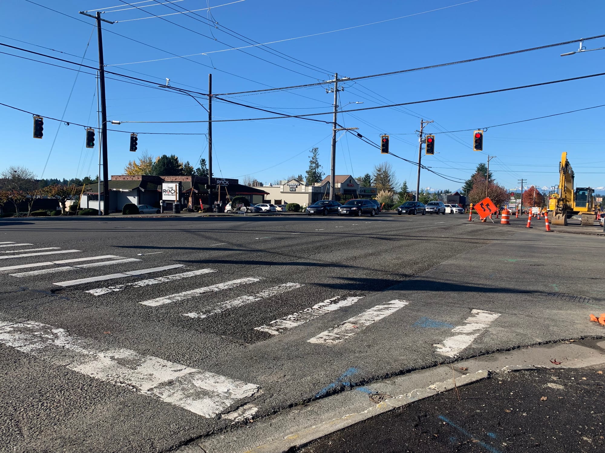 A photo of a wide traffic intersection with a painted pedestrian crossing and construction equipment.