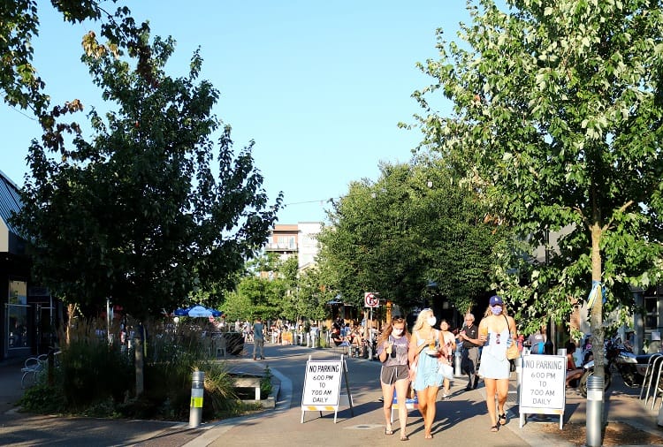 People walking in the street as two A Frame signs indicate no parking and block access