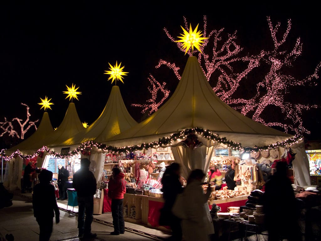 White tents decorated with garland and holiday lights.