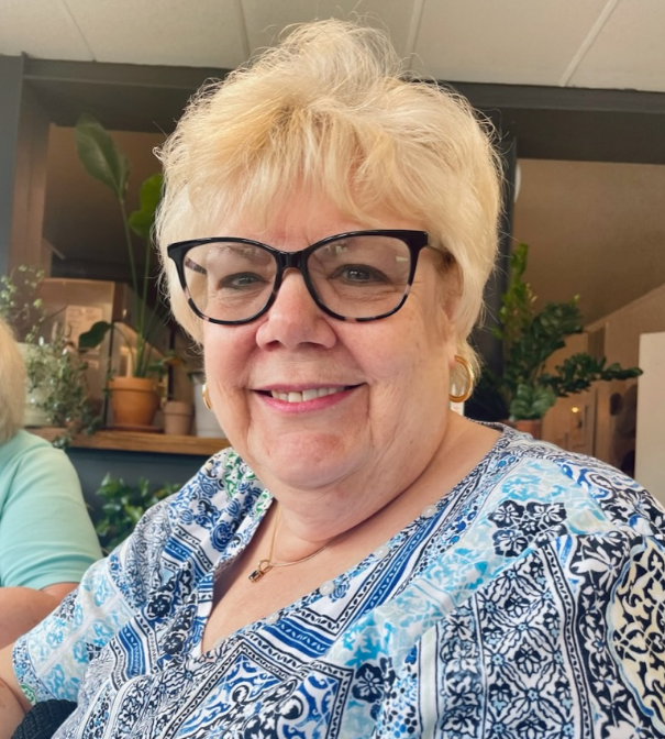 A blond woman in glasses and earrings.