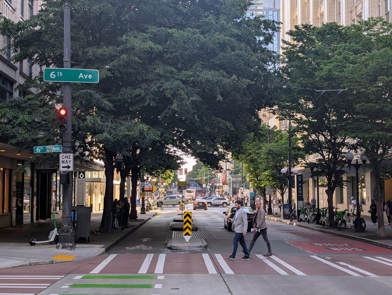 Two people cross the crosswalk at 6th Avenue.
