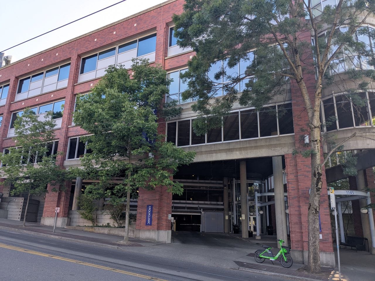 A four-story brick building with trees along the sidewalk.