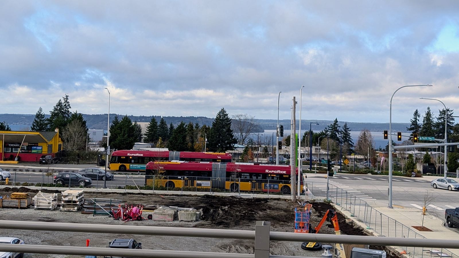 Puget Sound is visible to the west from the elevated stations along the ridgeline. Two A Line buses pass on SR 99.