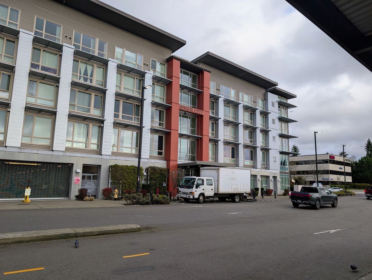 A five-story apartment building with a expanse of pavement in front leading to the transit center.